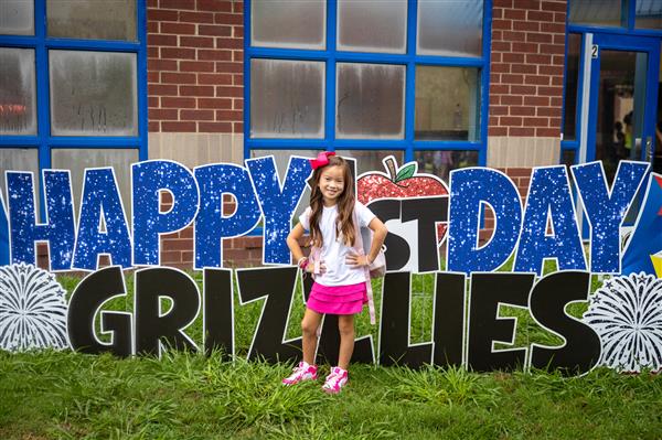 girl smiling next to happy first day grizzlies sign